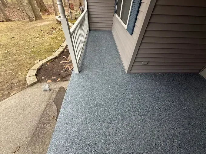 Front porch with speckled blue-gray floor, white railing, and brown siding.