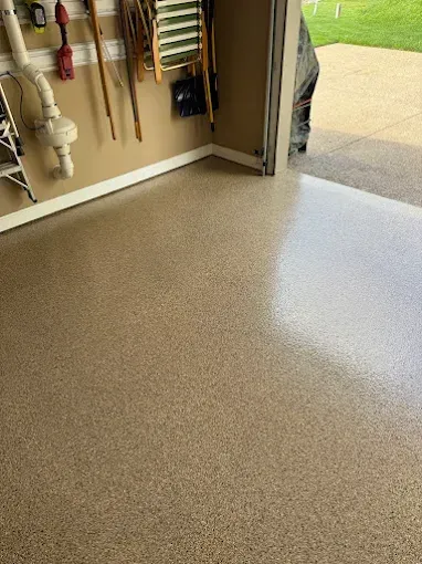 Garage with a speckled epoxy floor; tools on wall, partially open door to outside.