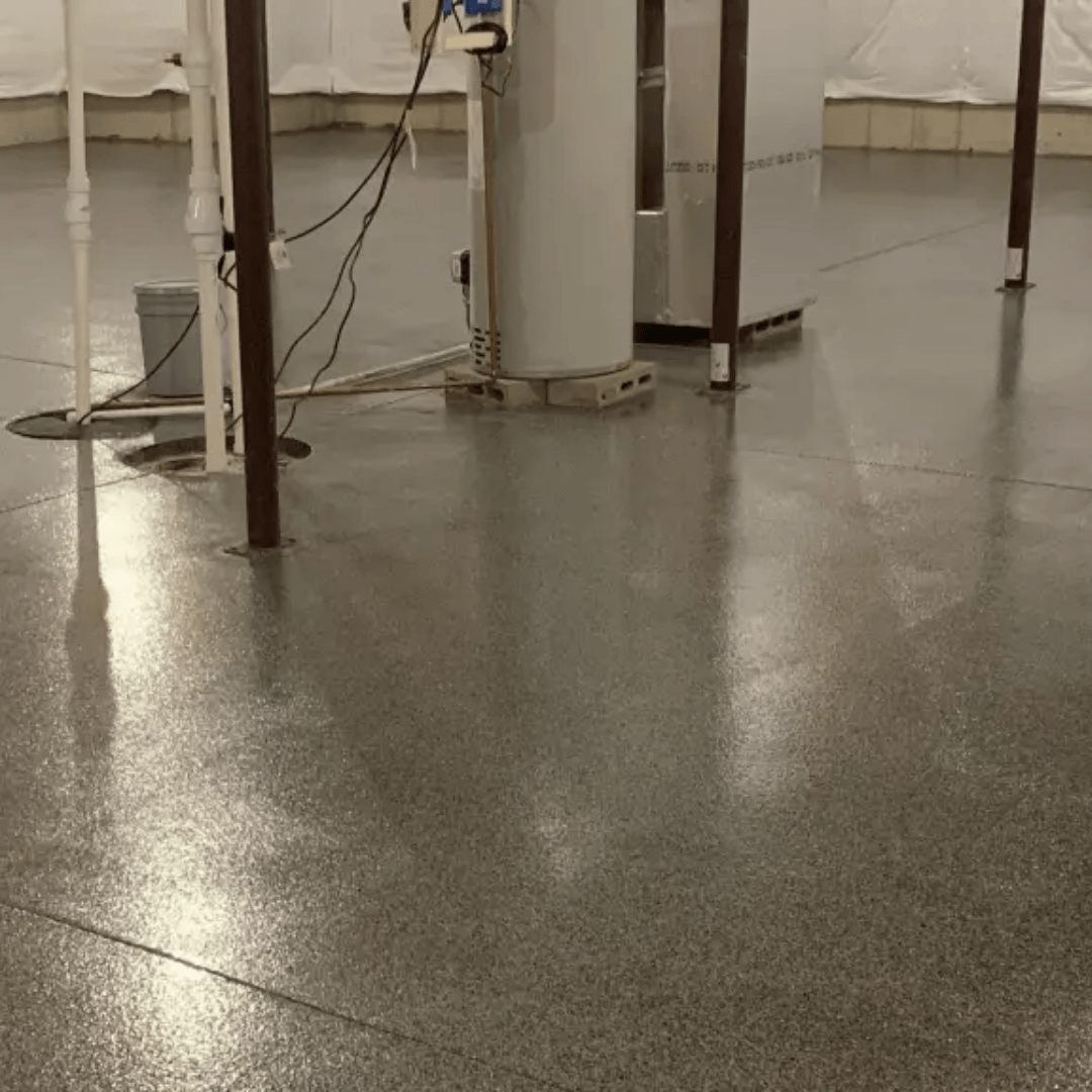Gray epoxy floor in a basement with support poles and equipment.