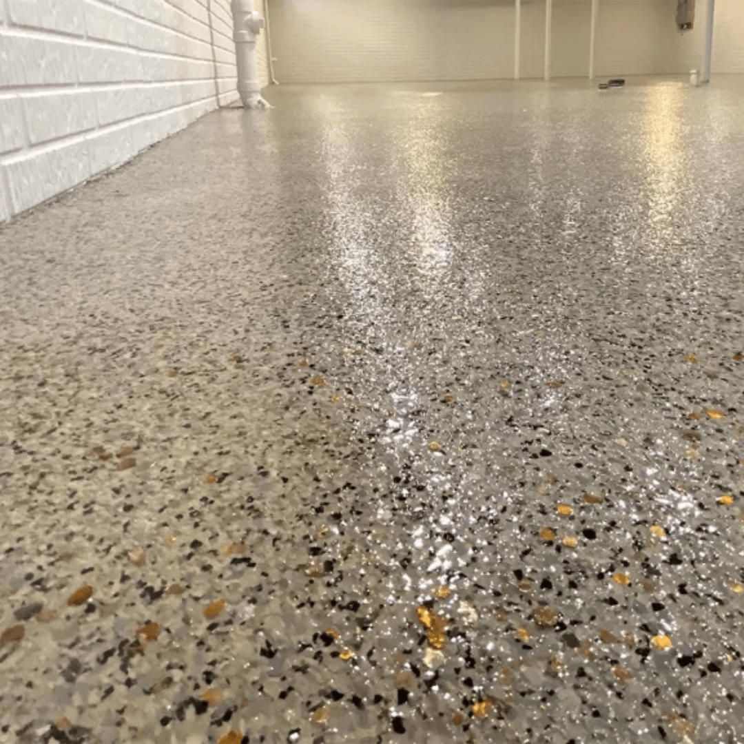 Glossy concrete floor speckled with gray, black, and gold chips, next to a white brick wall.