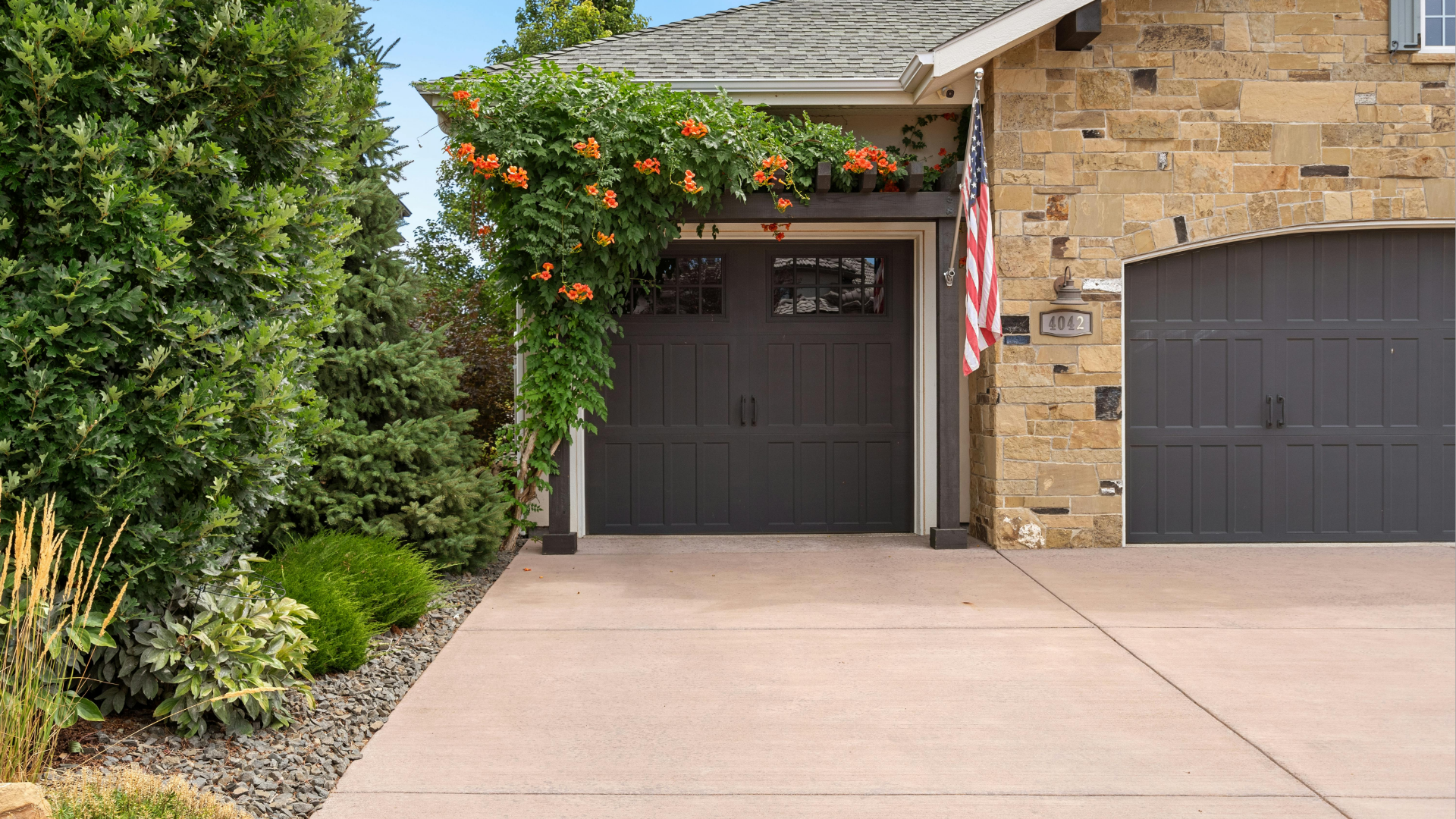 House exterior with stone facade, dark gray garage doors, and a concrete driveway.