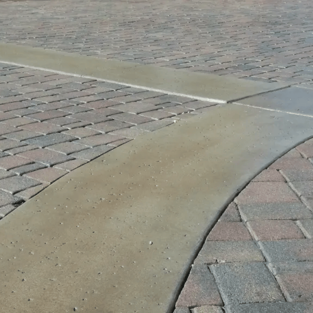 Brick pavers intersected by concrete strips on a walkway.