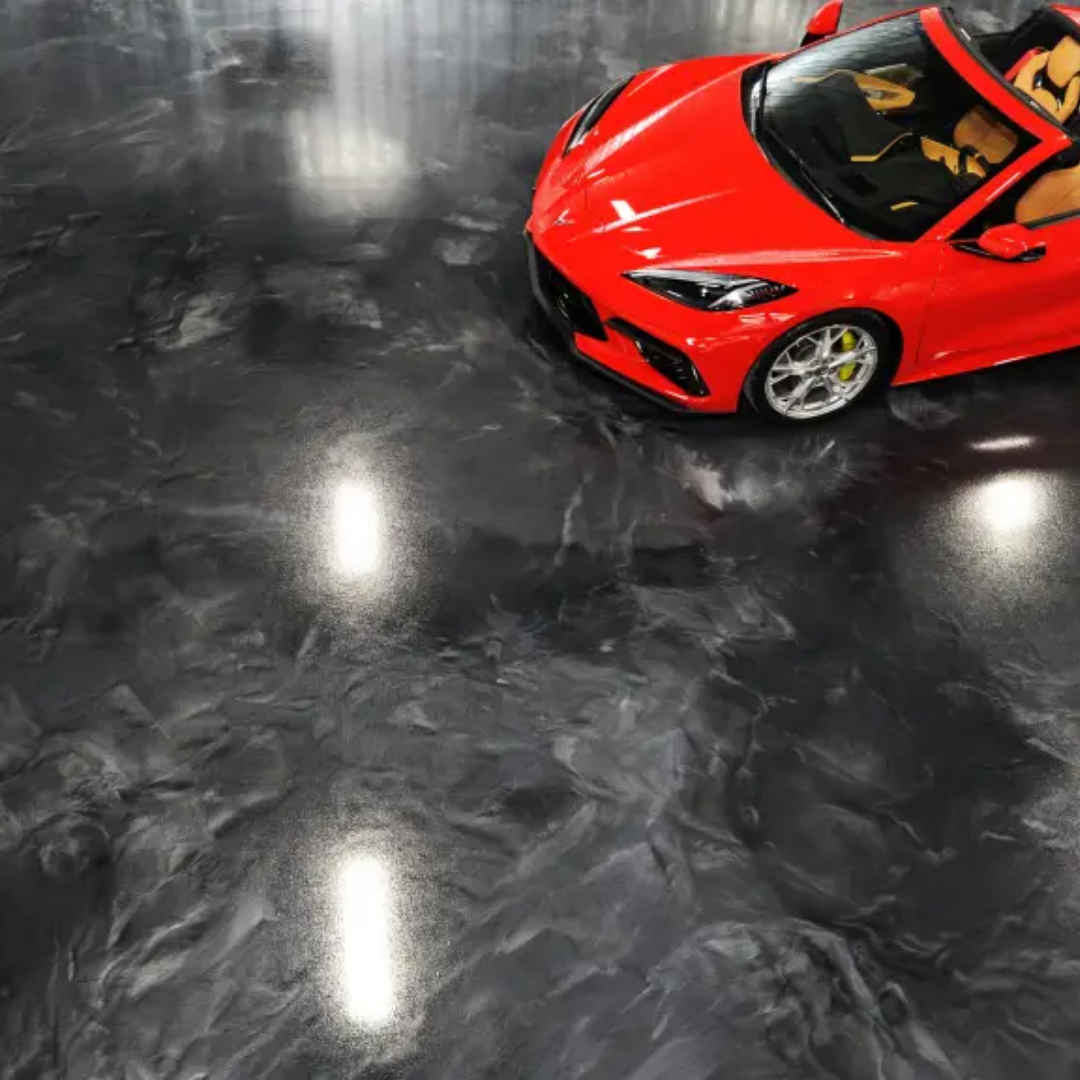 Red sports car on a dark, glossy epoxy garage floor with bright highlights.