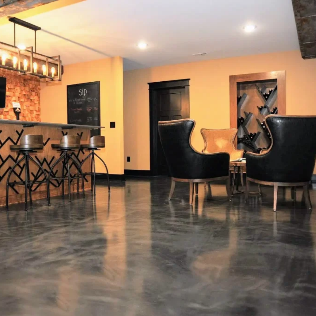 Room with bar and seating, dark glossy floor, orange walls, black chairs.