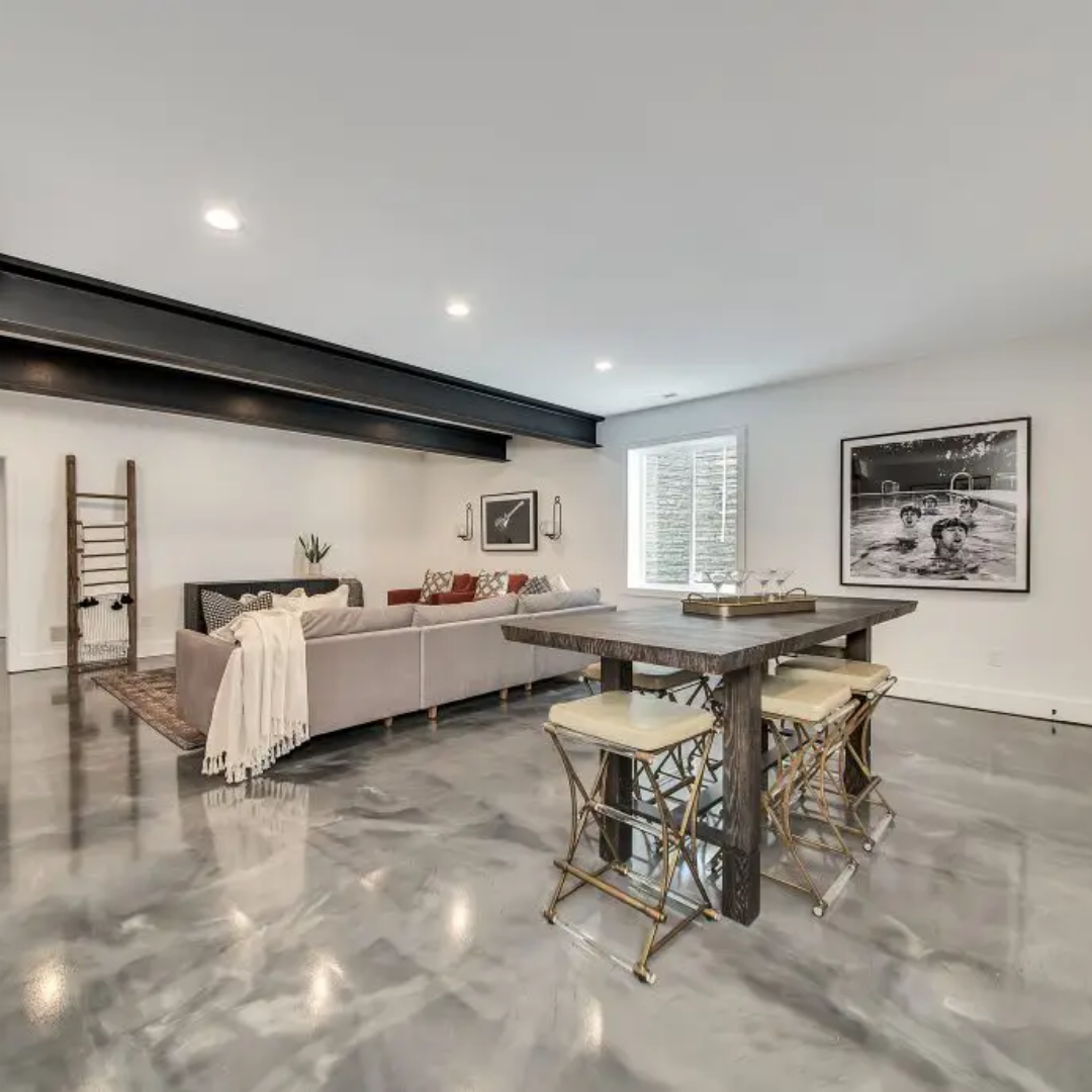 A finished basement with a bar table and stools, seating area, and polished concrete floor.