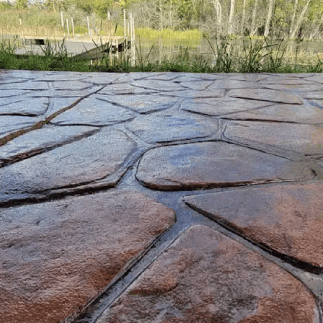 Stamped concrete patio, stone pattern, with water and trees in the background.