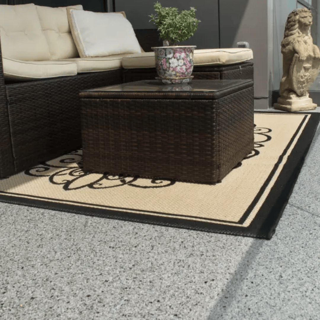 Outdoor patio furniture set on a patterned rug, a potted plant on the coffee table.