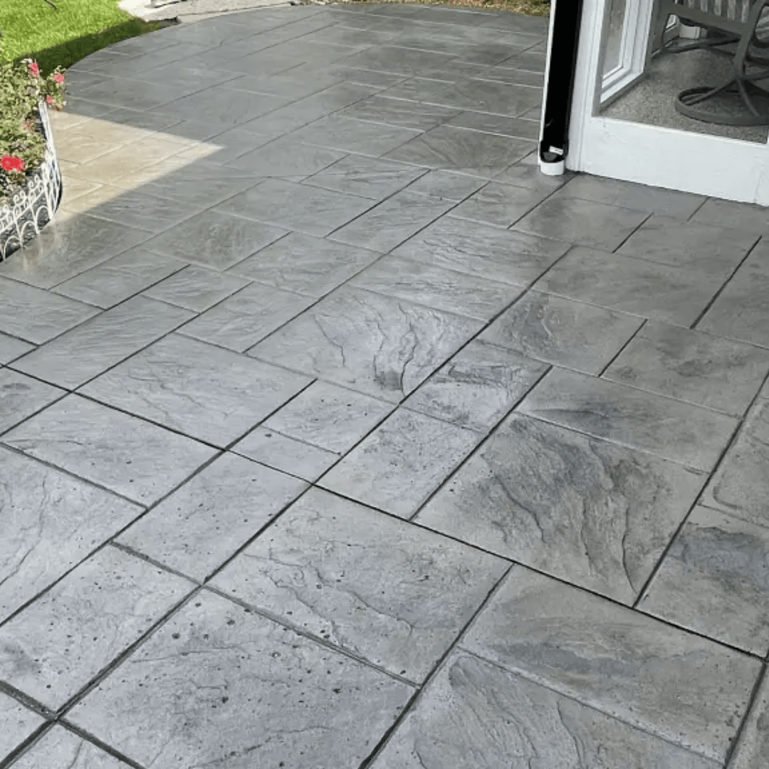 Gray stamped concrete patio with textured surface and rectangular tile pattern.