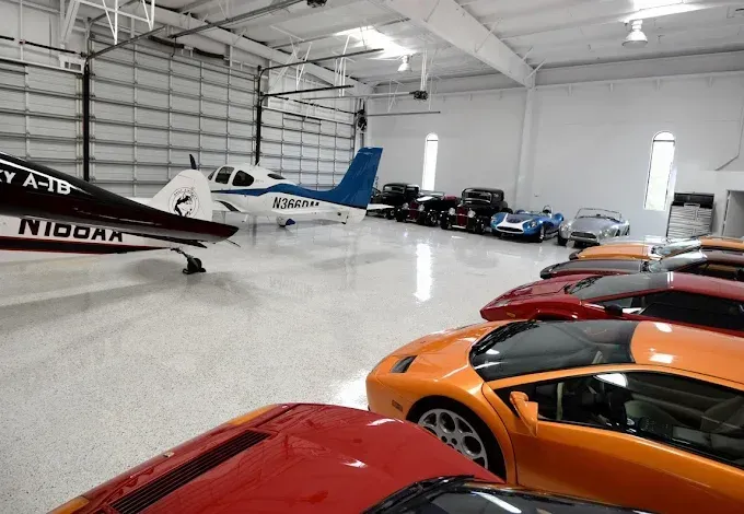 Luxury garage with a private airplane and several sports cars.