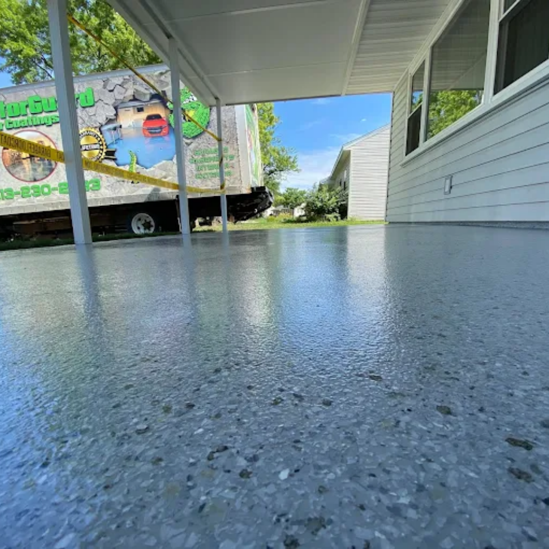 Gray, glossy, speckled concrete floor under a white overhang. A truck is in the background.