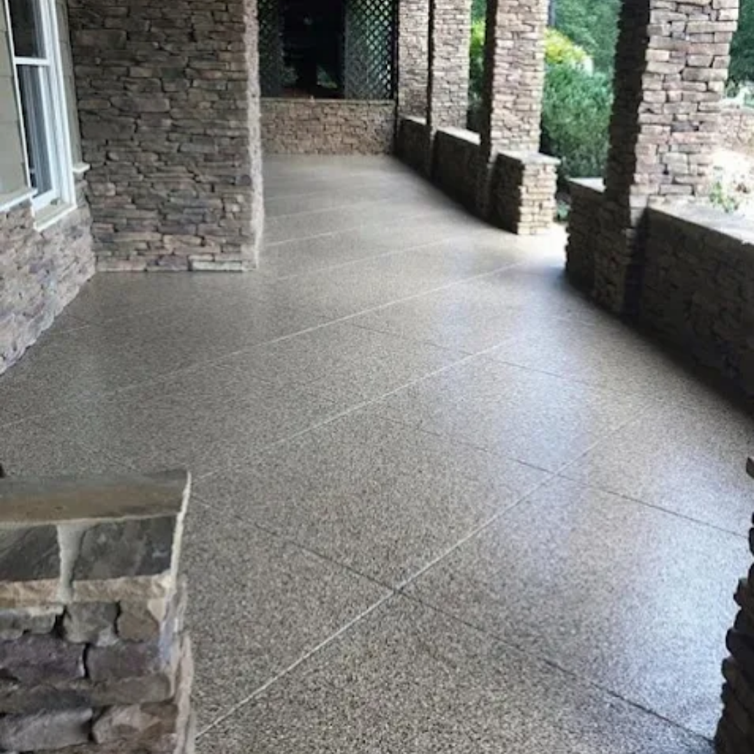 Stone-walled porch with gray speckled flooring, pillars, and decorative lines cut into the concrete.